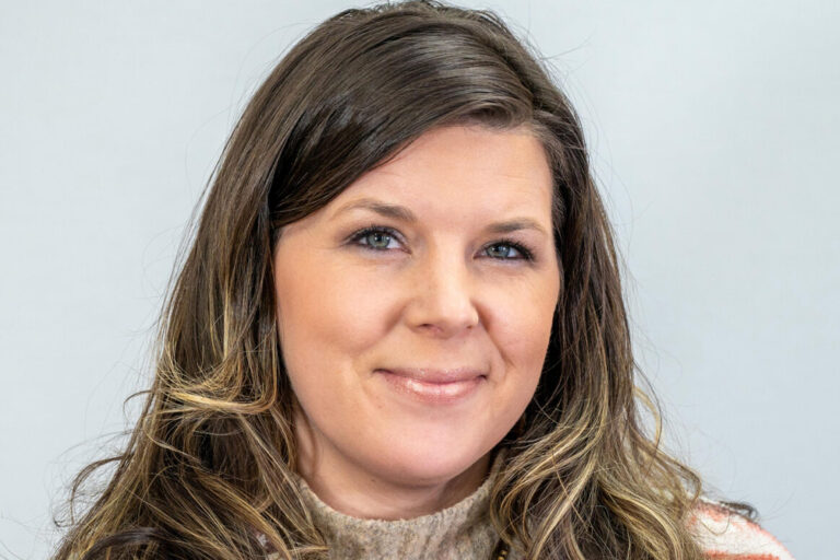 Headshot of woman smiling with long brown hair and turtleneck