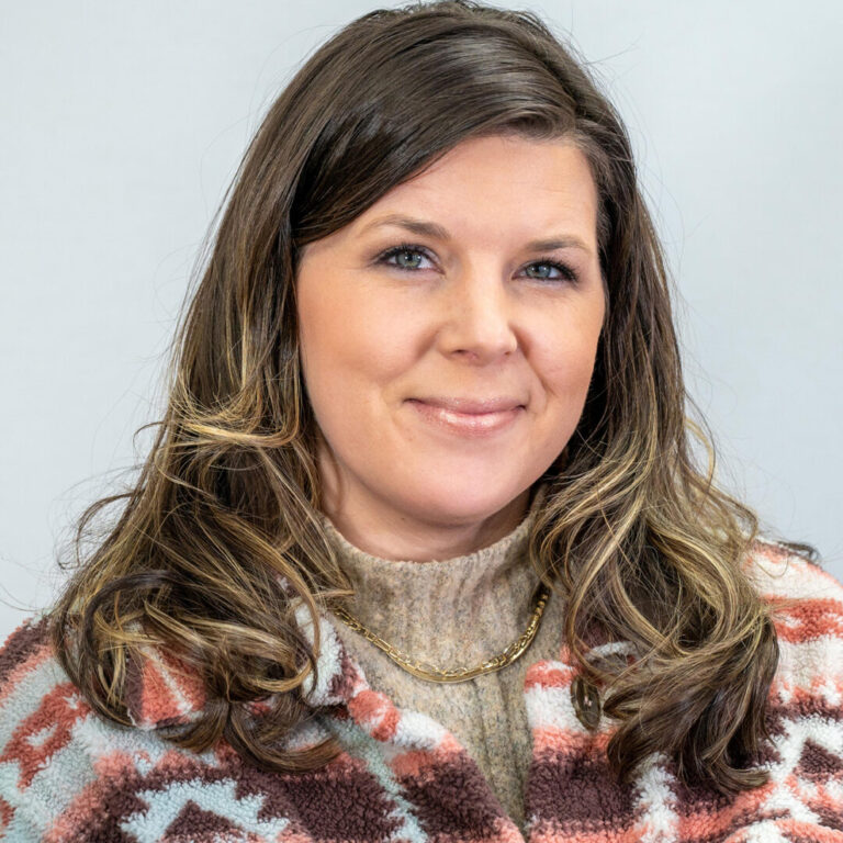 Headshot of woman smiling with long brown hair and turtleneck