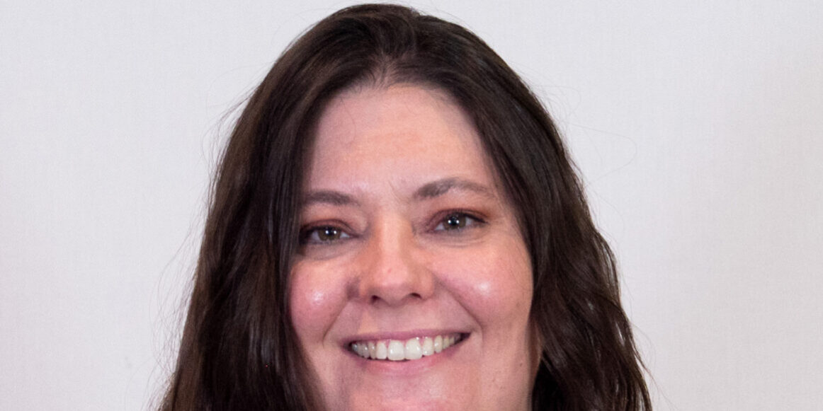 Woman with dark long hair, brown eyes, and light colored blouse