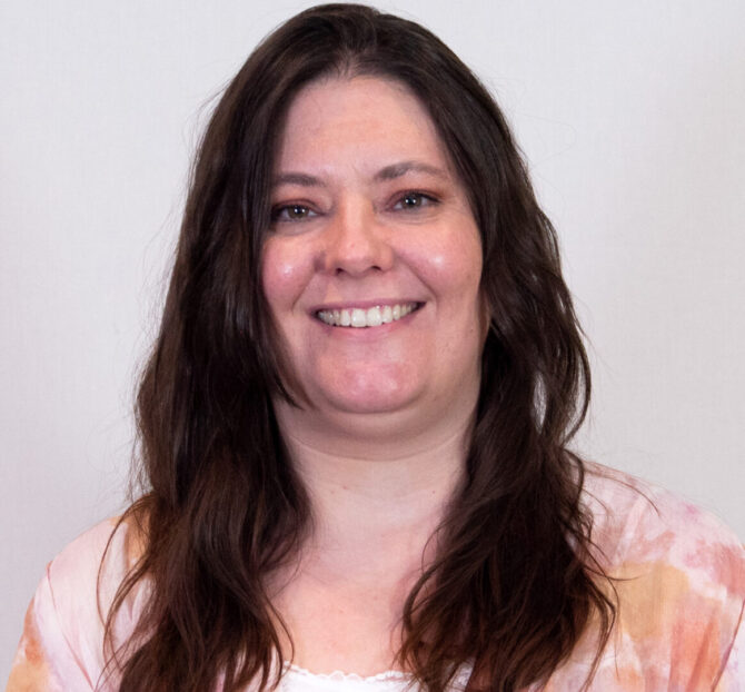 Woman with dark long hair, brown eyes, and light colored blouse