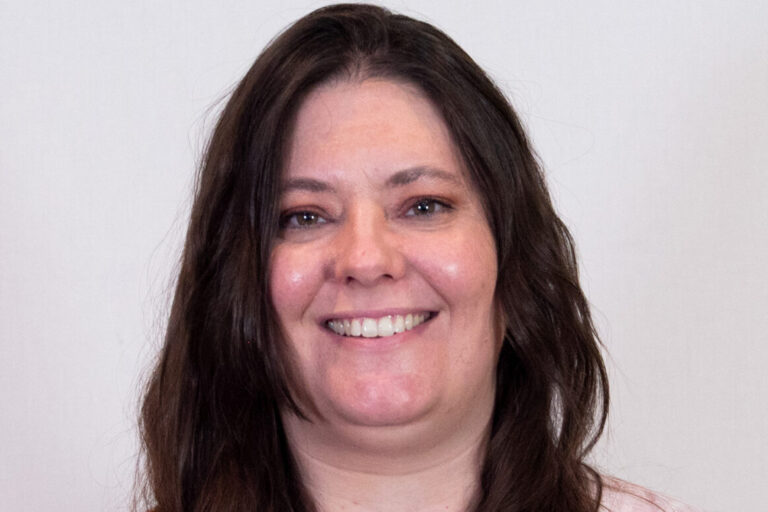 Woman with dark long hair, brown eyes, and light colored blouse