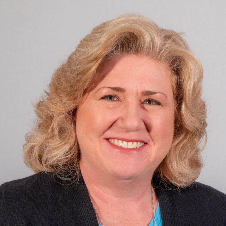 Woman with shoulder length blonde curled hair and black jacket