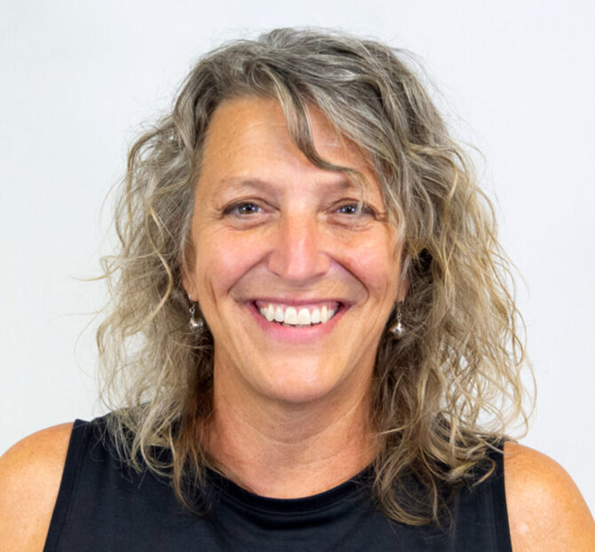 Woman with curly light hair and black tank top