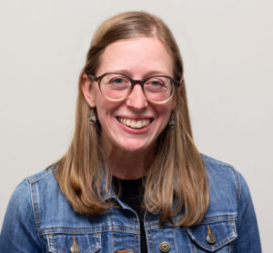 Headshot of smiiling woman with glasses and jean jacket