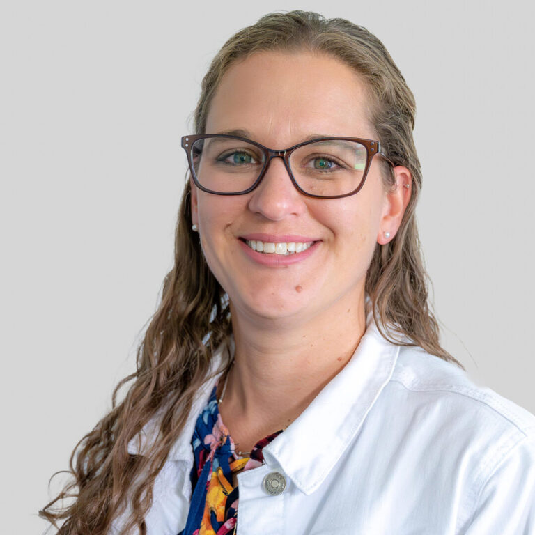 Woman with long hair and glasses heashot wearing a white coat