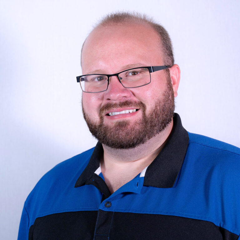 Man with black glasses, brown beard, and polo