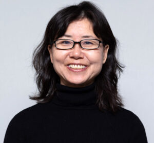 Woman with shoulder length black hair and glasses with a black turtleneck sweater