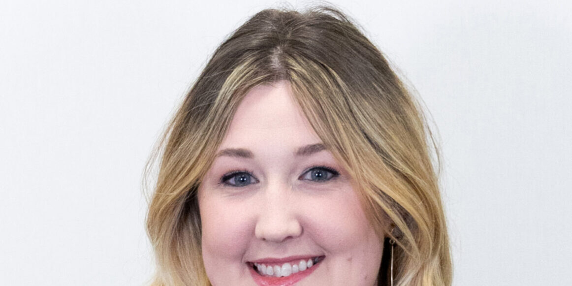 Headshot of woman with blonde curled hair and black and white blouse