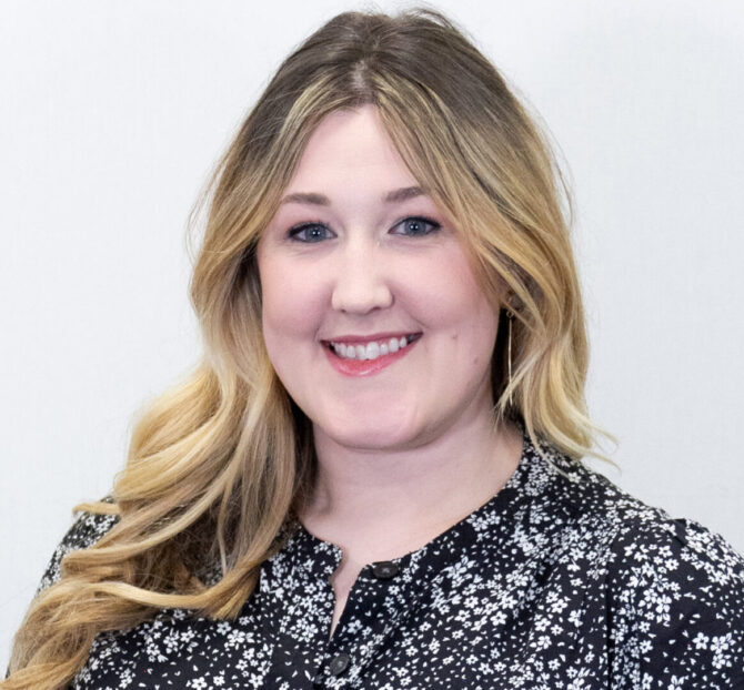 Headshot of woman with blonde curled hair and black and white blouse
