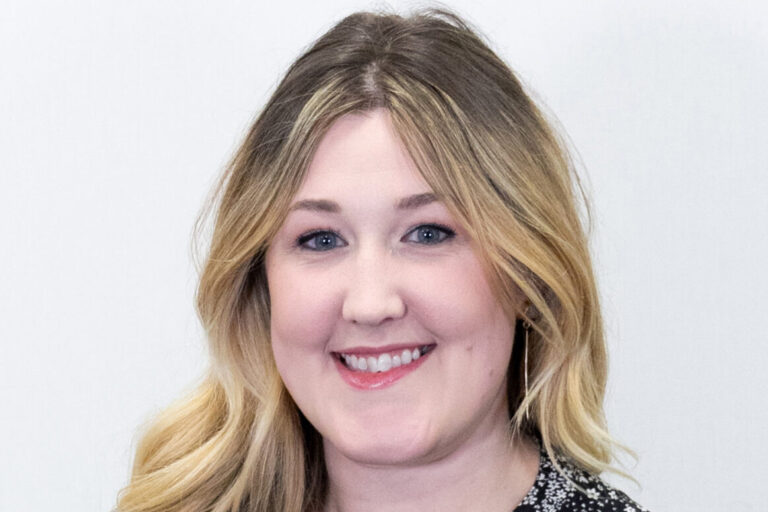Headshot of woman with blonde curled hair and black and white blouse