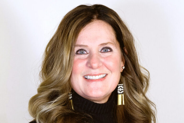 Headshot of woman with long brown hair smiling with a black turtleneck