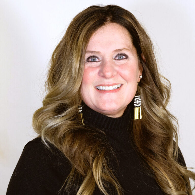 Headshot of woman with long brown hair smiling with a black turtleneck