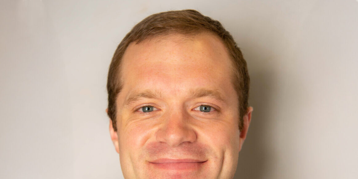 Man with brown hair and gray quarter zip