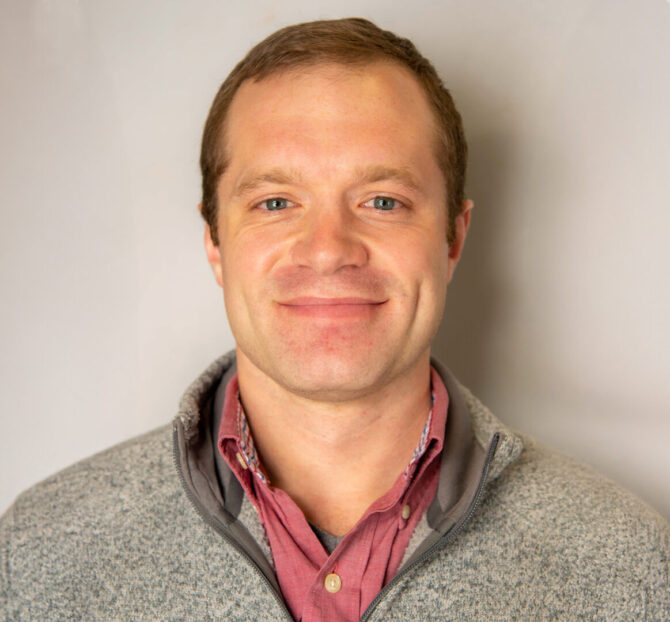 Man with brown hair and gray quarter zip