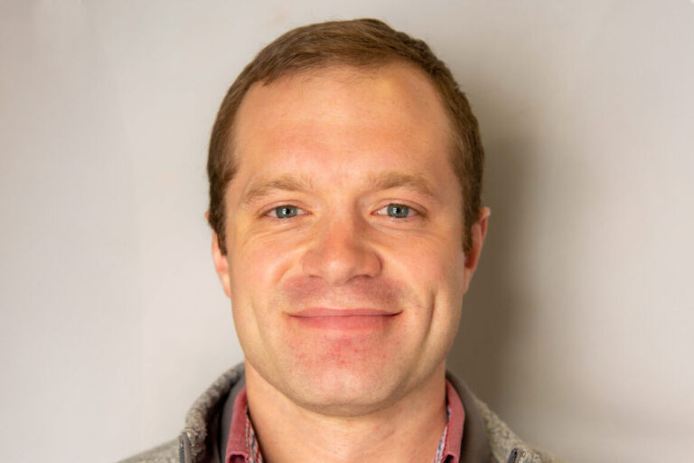 Man with brown hair and gray quarter zip