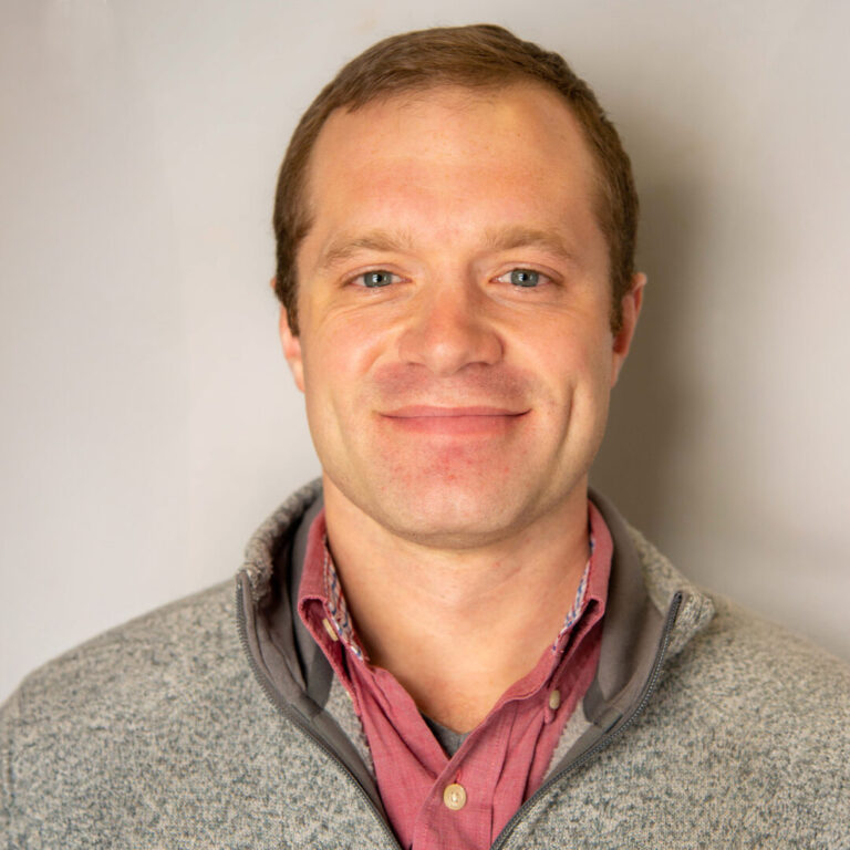 Man with brown hair and gray quarter zip