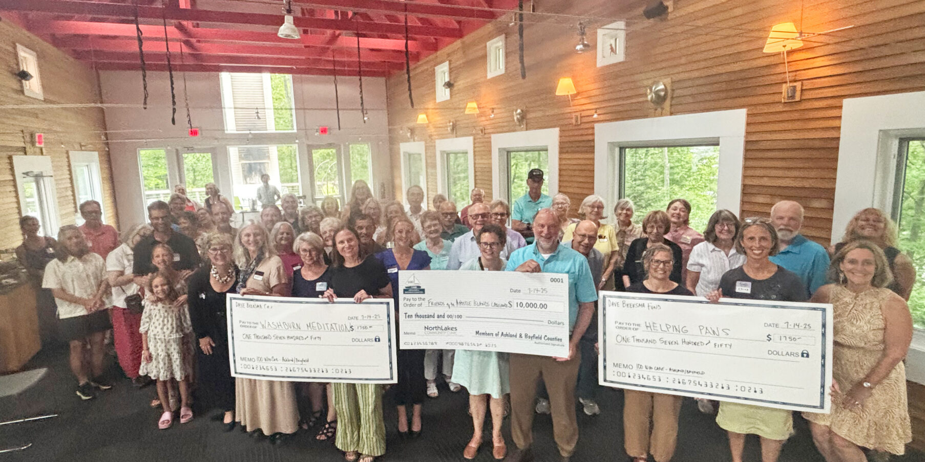 large group of people holding three large checks