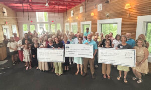 large group of people holding three large checks