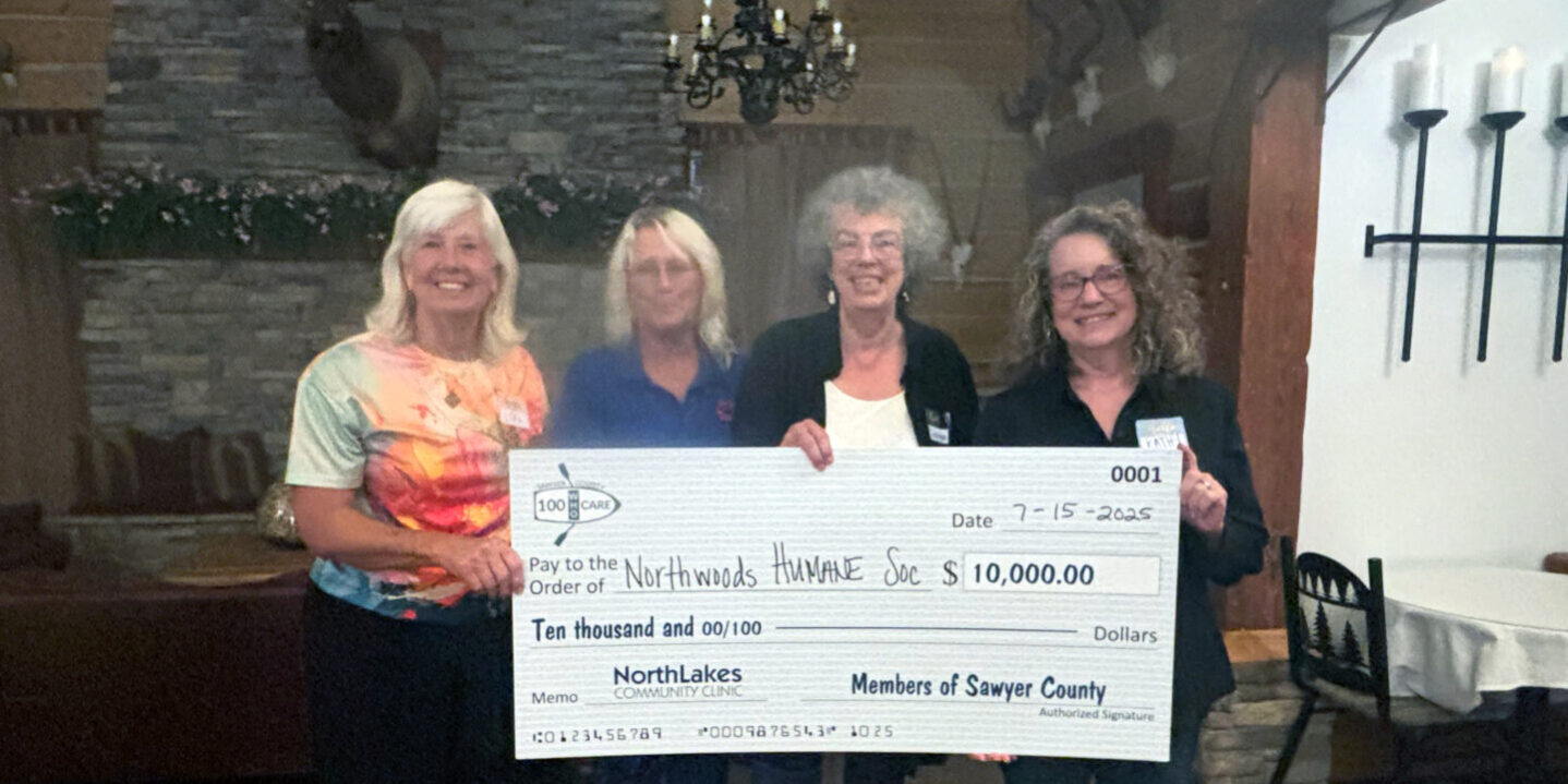 Four people holding a big check in front of a fire place
