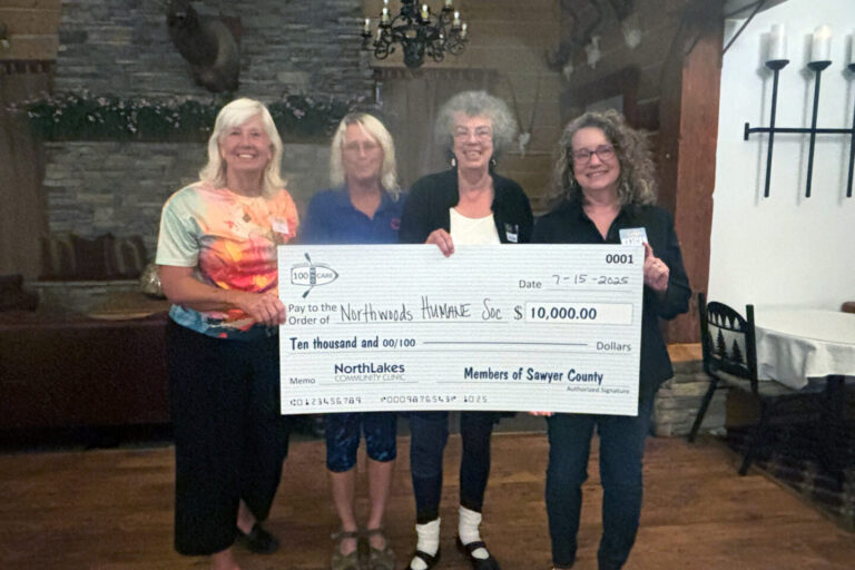 Four people holding a big check in front of a fire place