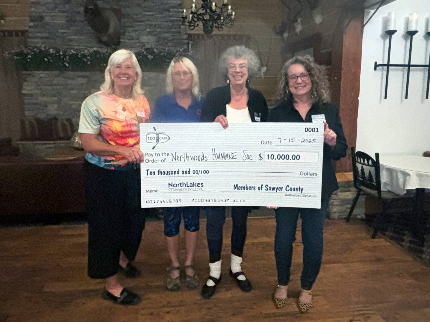 Four people holding a big check in front of a fire place