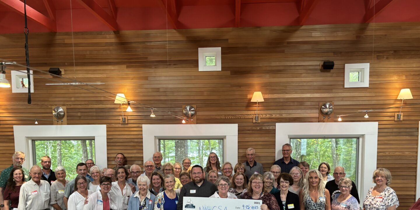 Large group of men and women in resturant around people holding a check for $10,000