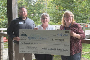 Three people holding large check outside