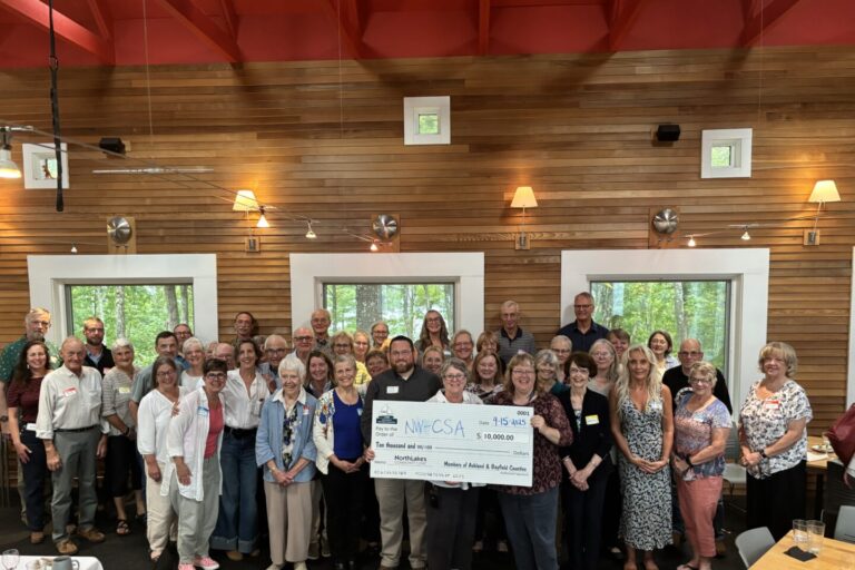 Large group of men and women in resturant around people holding a check for $10,000