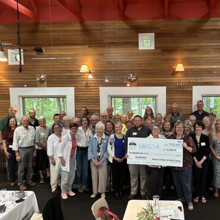 2025 R3 ASHBAY Large group of men and women in resturant around people holding a check for $10,000