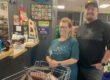 Woman and man with a grocery cart smiling at the checkout counter