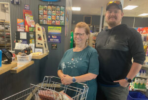 Woman and man with a grocery cart smiling at the checkout counter