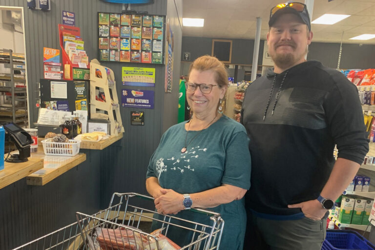 Woman and man with a grocery cart smiling at the checkout counter