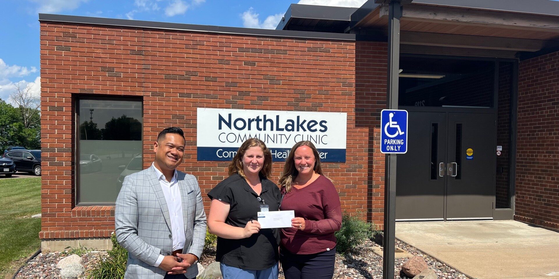 Three people in front of brick facade outside posing