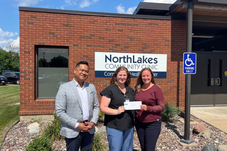 Three people in front of brick facade outside posing