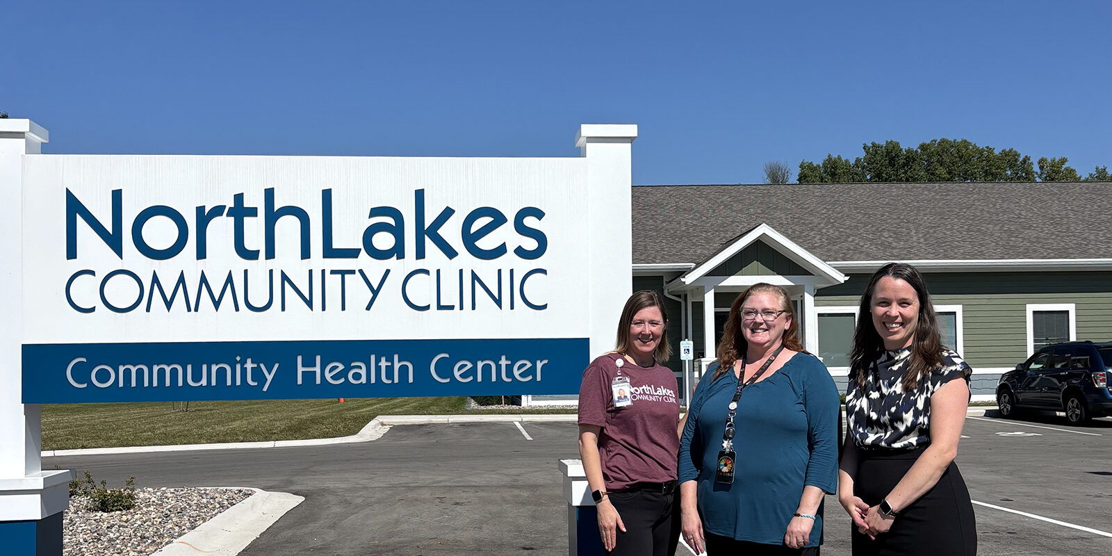 three women in front of sign outside