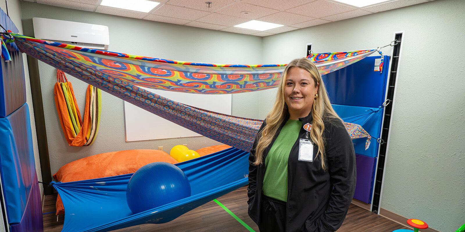 Woman in room with colorfull fabric draped behind