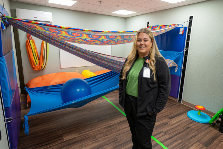 Woman in room with colorfull fabric draped behind