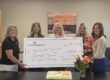 group of women holding large check