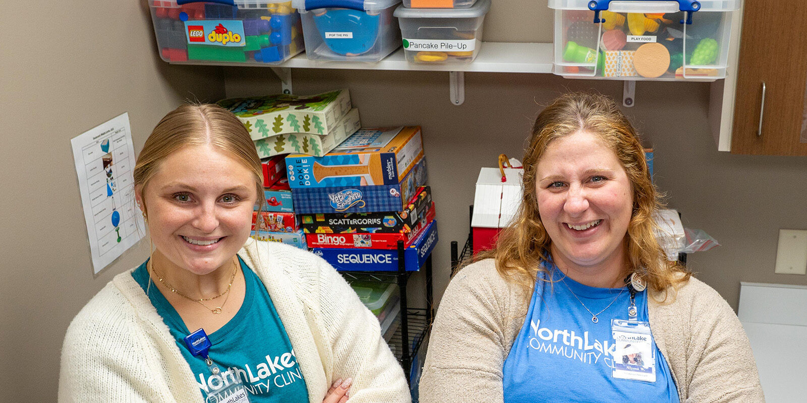 Two women smiling at camera with kid games behind them.