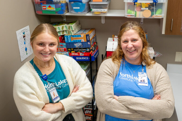 Two women smiling at camera with kid games behind them.